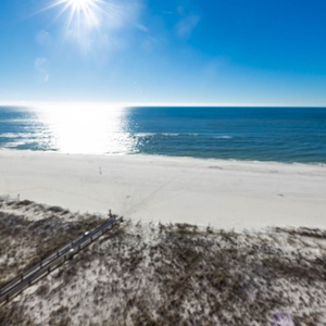 A bright view showcases the shimmering water and white sand beach, inviting relaxation under the clear blue sky