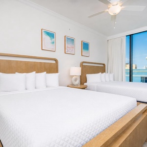 Relax in the guest bedroom featuring two queen beds, soft linens, and large windows with stunning views