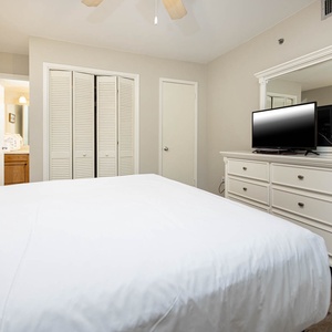 Realx in this guest bedroom featuring a queen bed, a TV, and stylish white furniture for a cozy retreat