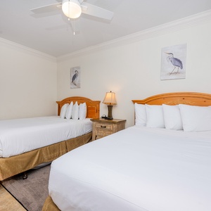This guest bedroom features two comfortable beds, soft white linens, and charming artwork for a relaxing stay