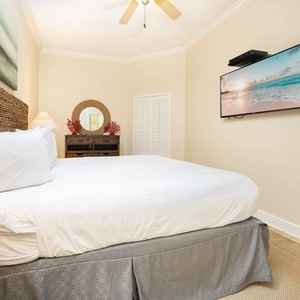 Cozy guest bedroom featuring a plush king bed, stylish decor, and a wall-mounted TV for your entertainment