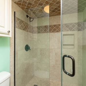 Modern master bath featuring a sleek glass walk-in shower with elegant tile accents and a refreshing mint green wall
