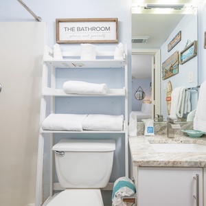 The guest bathroom features a stylish blue shower curtain, plush towels, and a sleek granite countertop for a refreshing experience