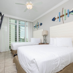 Inviting guest bedroom with two comfortable queen beds, a TV, and large windows