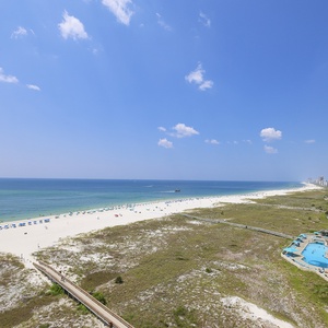 Expansive view of the beach with white sand, colorful umbrellas, and a coastline view perfect for sunsets