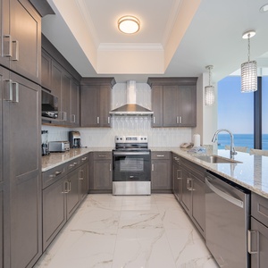 Prepare meals in this stylish kitchen featuring sleek cabinetry, modern appliances, and a scenic beachfront view