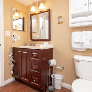 Warmly decorated bathroom featuring a stylish vanity with granite countertop, ample storage, and plush towels neatly arranged
