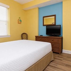The guest bedroom features cheerful yellow walls, a TV for entertainment, and a comfortable bed for a restful stay