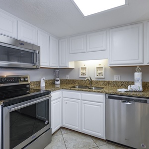 Kitchen features white cabinetry, granite countertops, and stainless appliances, creating a bright and functional space