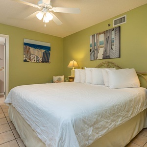 Green walls complement the guest room with an inviting king bed, with beach artwork enhancing the room's relaxed vibe