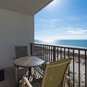 Enjoy a serene beachfront view from this cozy balcony, featuring a small table and two chairs for relaxation