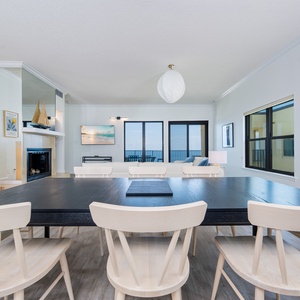 Open dining area with a large black table, stylish chairs, and panoramic views through expansive windows