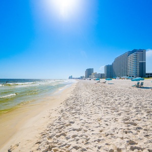 Experience the beautiful beachfront with soft sand, gentle waves, and vibrant beachgoers for a perfect day by the water