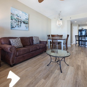 Cozy living area features a brown leather sofa with queen sleeper, glass coffee table, and dining space