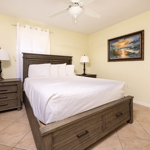 This cozy guest bedroom features a queen bed with soft linens, bedside tables, and a decorative painting on the wall