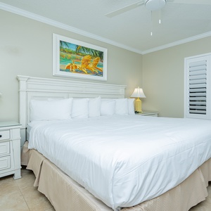 Relax in this serene guest bedroom featuring a king bed, soft linens, and cheerful coastal artwork for a restful retreat