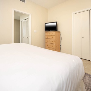 Guest bedroom featuring a comfortable king bed, a dresser with a TV, and closet space for convenient storage