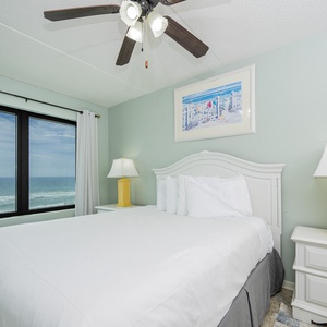 The master bedroom features a comfortable bed and stunning beachfront views through large windows