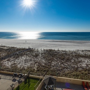 Serene beachfront view showcases glistening water and white sand, with a peaceful beach path visible in the foreground