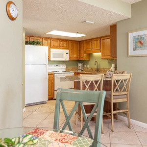 Cook and dine in the inviting kitchen area featuring warm wood cabinetry and a cozy breakfast bar for shared meals