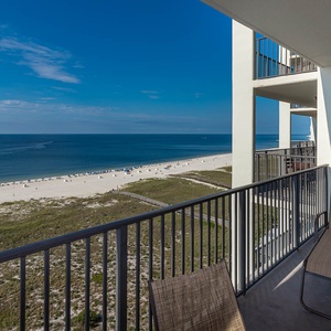 Balcony view showcasing the beach with white sand, lounge chairs, and a serene gulf stretching under a clear blue sky