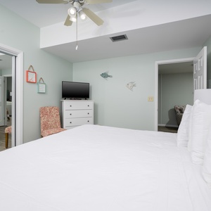 This cozy guest bedroom features a plush king bed, a TV for entertainment, and soft blue walls for a tranquil atmosphere