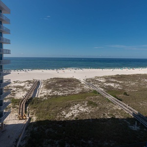 Gulf views stretch across the beach, with lounge chairs dotting the white sand and a wooden walkway leading to the shore