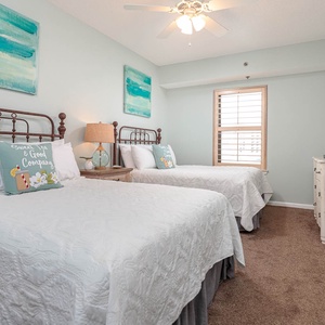 Two cozy double beds adorned with white quilts and decorative pillows create a welcoming vibe in this inviting guest room