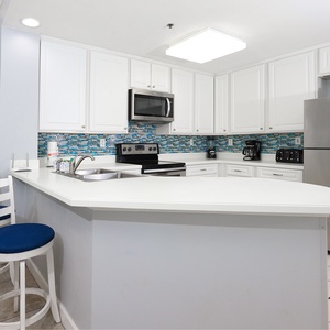 The kitchen features white cabinets, stainless appliances, and a vibrant tile backsplash, perfect for culinary adventures