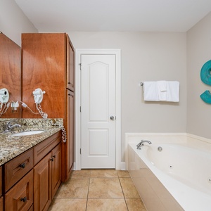 The master bath features a granite countertop, a relaxing jetted tub, and a beach-themed decor for a refreshing getaway