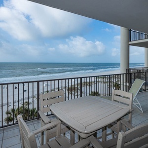 Enjoy breathtaking beachfront views from this balcony, featuring a spacious table and comfortable seating for relaxation
