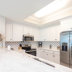 Prepare meals in this kitchen with elegant cabinetry, stainless appliances, and stylish backsplash