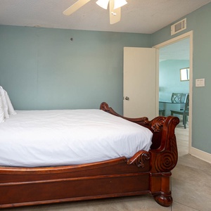 This guest bedroom features a beautifully carved wooden queen bed, soft white linens, and a serene beach vibe