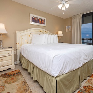 Cozy master suite features a king bed, decorative rug, and access to a balcony with views of the beach and gulf waters