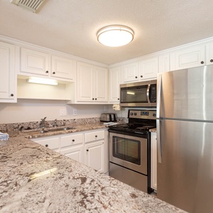 This kitchen features stainless appliances, granite countertops, and ample cabinetry for a delightful cooking experience