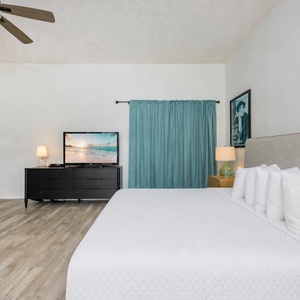 Spacious guest bedroom featuring a cozy king bed, two twin bunk beds, and a TV for relaxing evenings