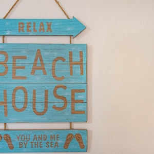 This charming beach house sign in vibrant blue adds a cheerful touch, inviting guests to relax and enjoy their stay