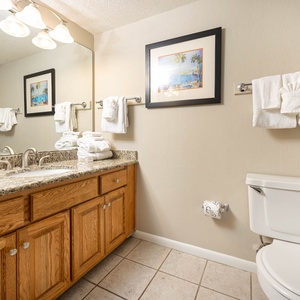 Refresh in this guest bathroom, featuring a granite countertop, ample towels, and a colorful shower curtain