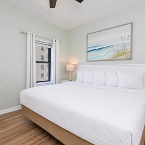 King bed in the guest suite invites you to sink into comfort beneath soft lamps and serene coastal art