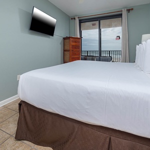 Inviting master bedroom with a comfortable king bed and a beach view through large windows that bring in natural light