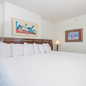 This cozy bedroom features a large bed with plush pillows, complemented by colorful artwork and soft lighting for relaxation