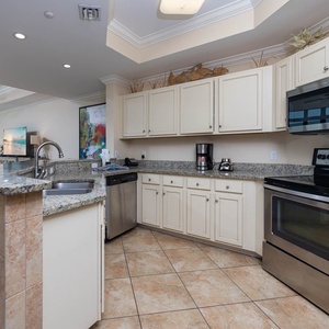 Modern kitchen featuring stainless appliances, granite countertops, and a view of the sparkling coastline