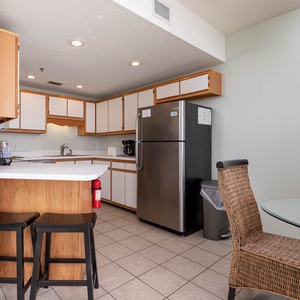Brightly lit kitchen features wood cabinetry, stainless appliances, and a breakfast bar with seating for casual dining