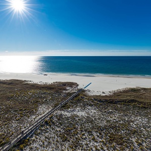 Vibrant beach stretches along the gulf, framed by natural dunes and a clear blue sky, inviting relaxation and exploration