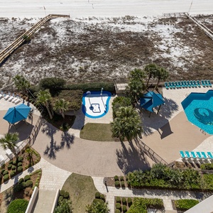 Enjoy the inviting pool area with lounge chairs, lush landscaping, and easy access to the beach just steps away