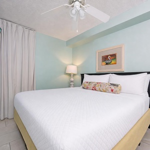 Relax in this serene bedroom featuring a comfortable king bed, soft aqua walls, and a cozy chair for reading