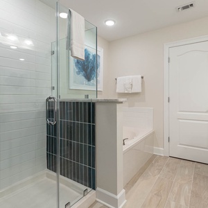 Enjoy a refreshing shower with dark tile accents or sink into the tub for a warm soak in the master bath
