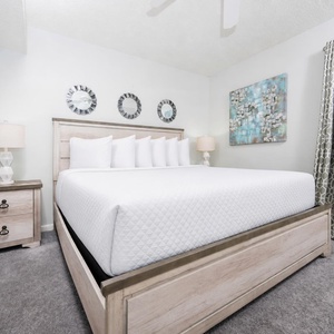 The cozy bedroom features a large king bed, a stylish nightstand, and decorative wall art for a serene vibe