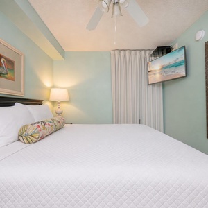 Sleep peacefully in this tranquil bedroom featuring soft bedding, king bed, a TV, and soothing teal walls for a relaxing vibe
