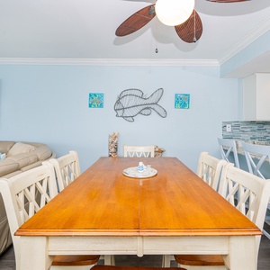 This inviting dining area features a warm wooden table, light blue walls, and a cozy living space with a large sectional sofa